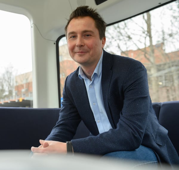 A picture of Harri Santamala smiling to the camera while wearing a navy blue jacket and a blue collar shirt with jeans.