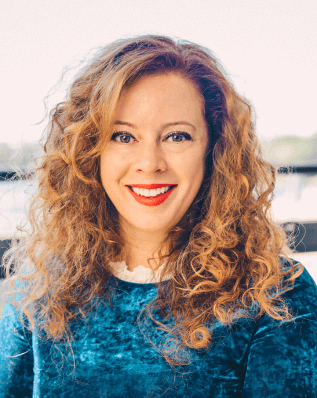 Curly-haired Leila Mojtahedi, Head of Digital Marketing at Wärtsilä, wearing a blue velvet shirt and red lipstick while smiling to the camera.