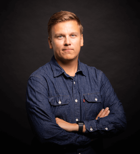 A picture of Simo Haakana, Enterprise Architect at Barona, in a denim shirt against a black background.